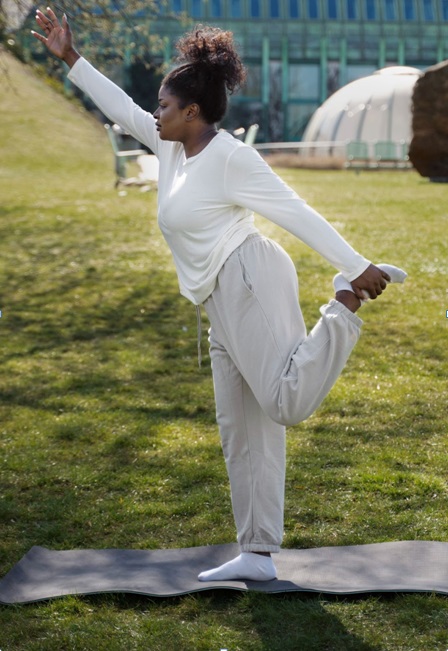 An African woman doing stretch exercises outdoors.