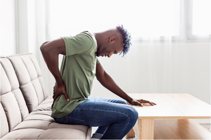 An African man holding his lower back in apparent pain.
