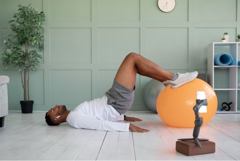 A black man on his back doing hip thrust using a soft ball
