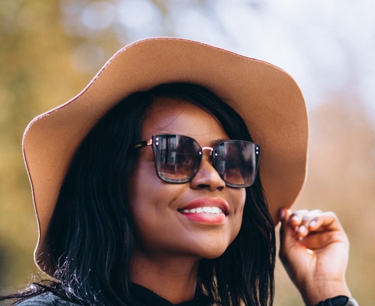A lack lady wering sunglasses and a wide-brimmed hat