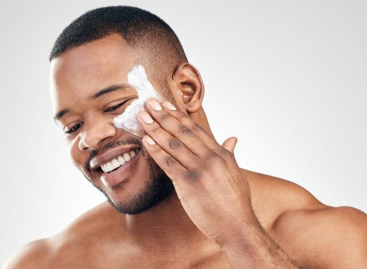 African man applying moisturiser on his face