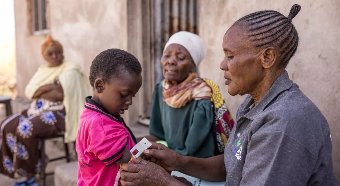 An Africa Community Health Worker measures a boy's arm to detect malnutrition.