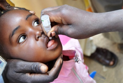 An Arican child receiving oral polio vaccine from a healthcare worker