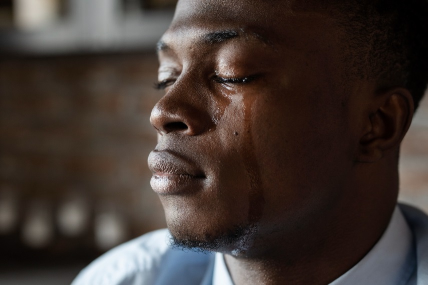 A young African male with tears rolling down his cheeks
