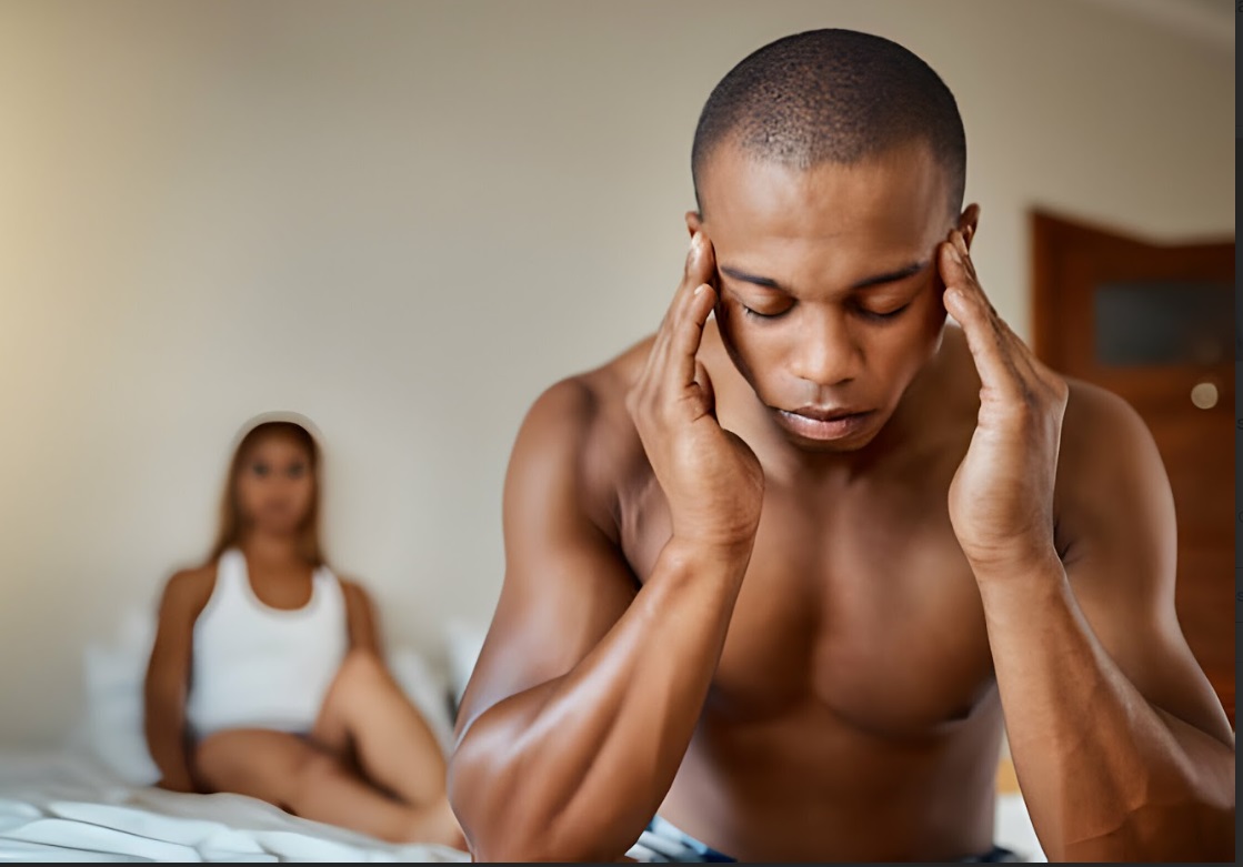 Black man sitting on a bed holding both sides of heaad due to suspected sex headache