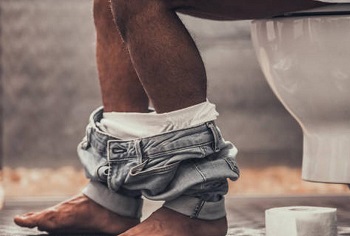A black man sitting on a toilet bowl