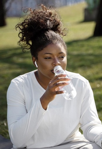 A black lady drinking water from a bottle