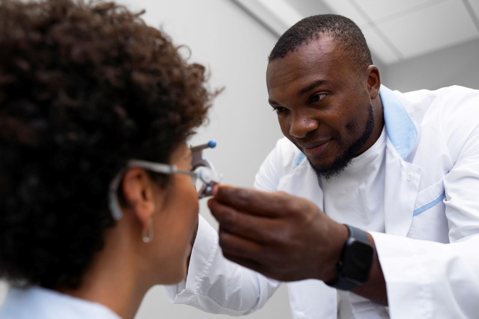 A black male optometrist performing eye measurement screen on a black lady for her eye glasses