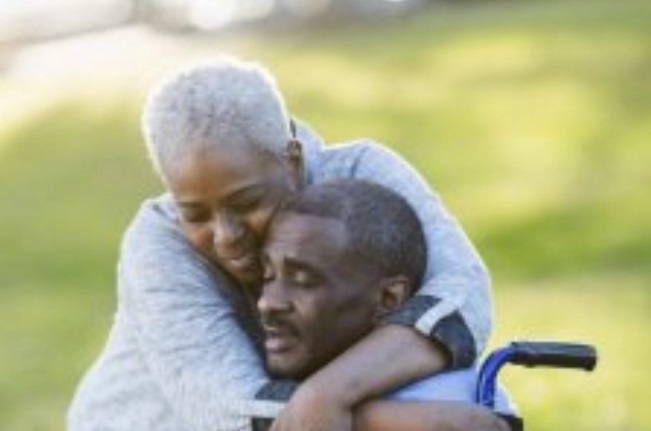 Caregiver hugging stroke survivor in a wheel chair