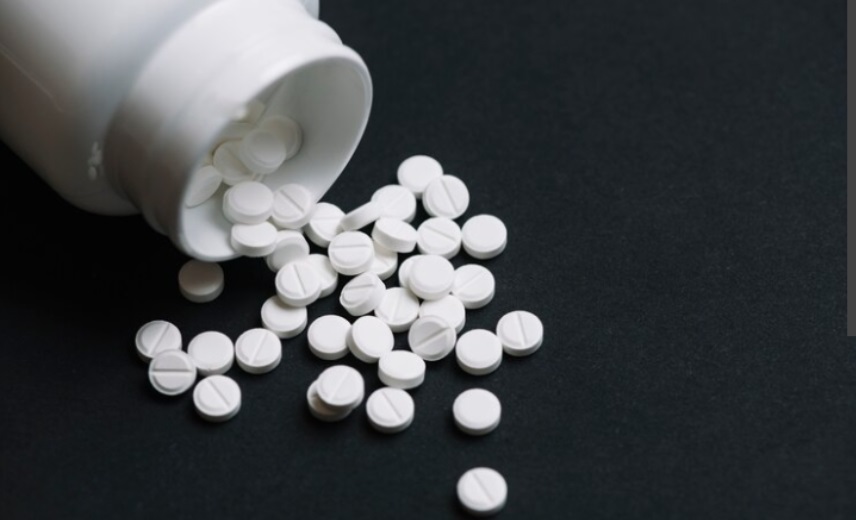 Diazepam tablets poured from a plastic bottle onto a dark table top