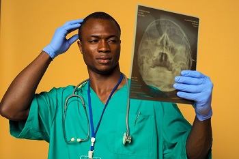 A medical professional holding a radiograph of a head scan