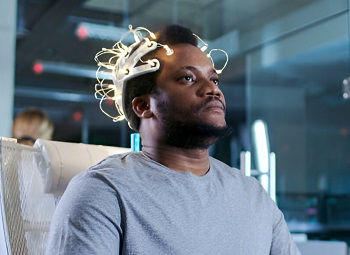 A black man wearing brainwave scanning headset in a brain study laboratory