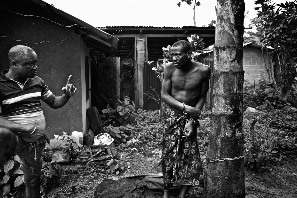 Image of a maltreated mentally ill African male chained to a tree.