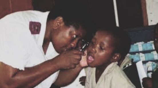 A nurse checking the ear of a child student