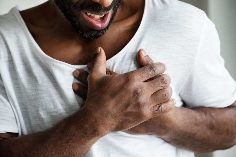 Partial image of an African man holding chest in pain, indicating possible heart attack or heart disease symptoms.