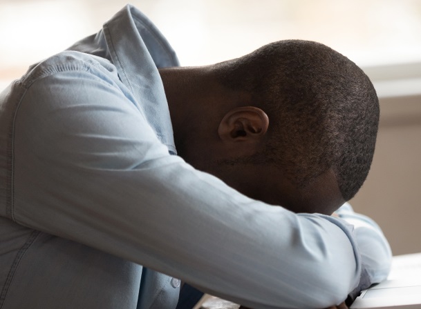 Young black male sleeping with head on his arms on a table