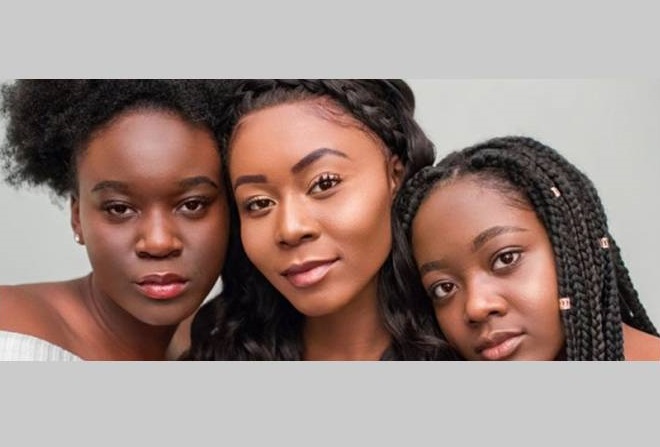 Three young women standing together with heads touching