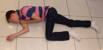 A child lying on his right side on the floor, unresponsive