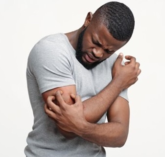 Young black man scratching his itching right arm with his left hand