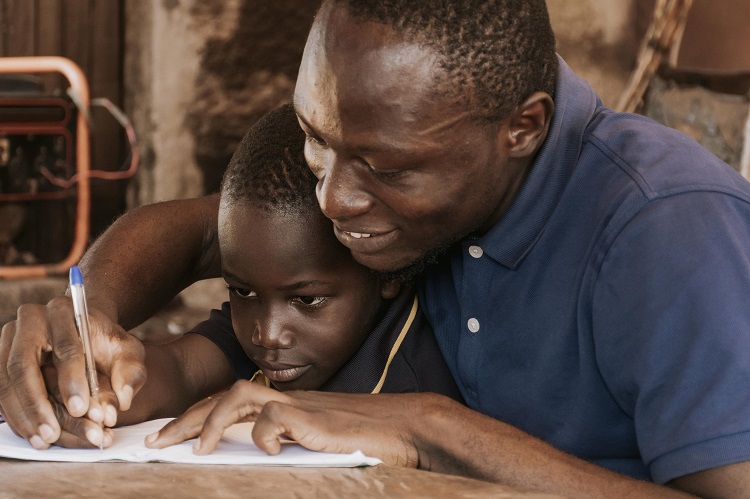 a middle aged African father teaching his son to write
