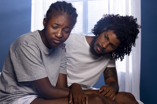 Black couple in bedroom with male partner probing his female partner;s feelings