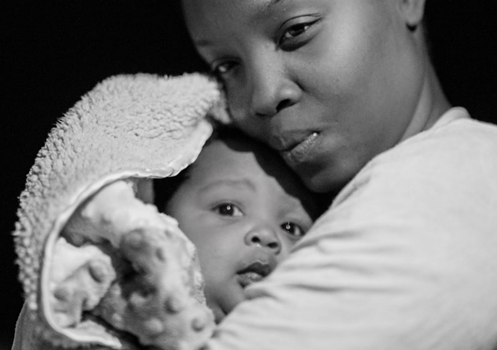 Close up black and white image of an African mother holding her baby outdoors