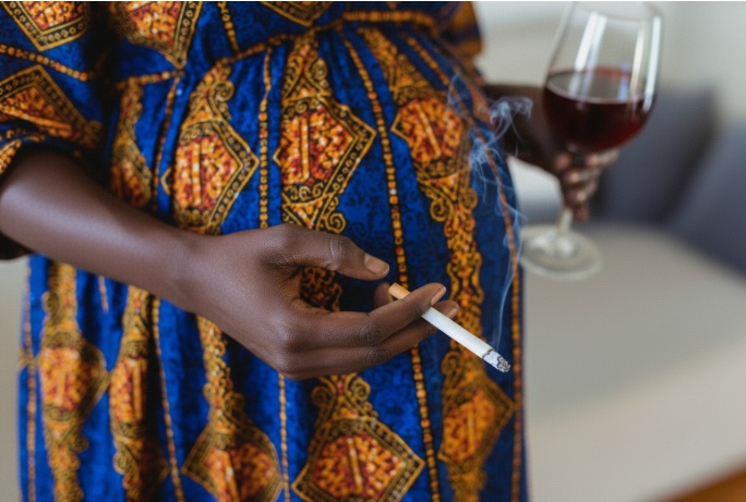 Partial photo of an African woman with cigarette in one hand and a glass of wine in the other