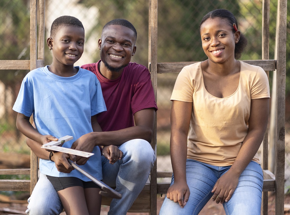 Seated and happy African fparents posing outdoor with son