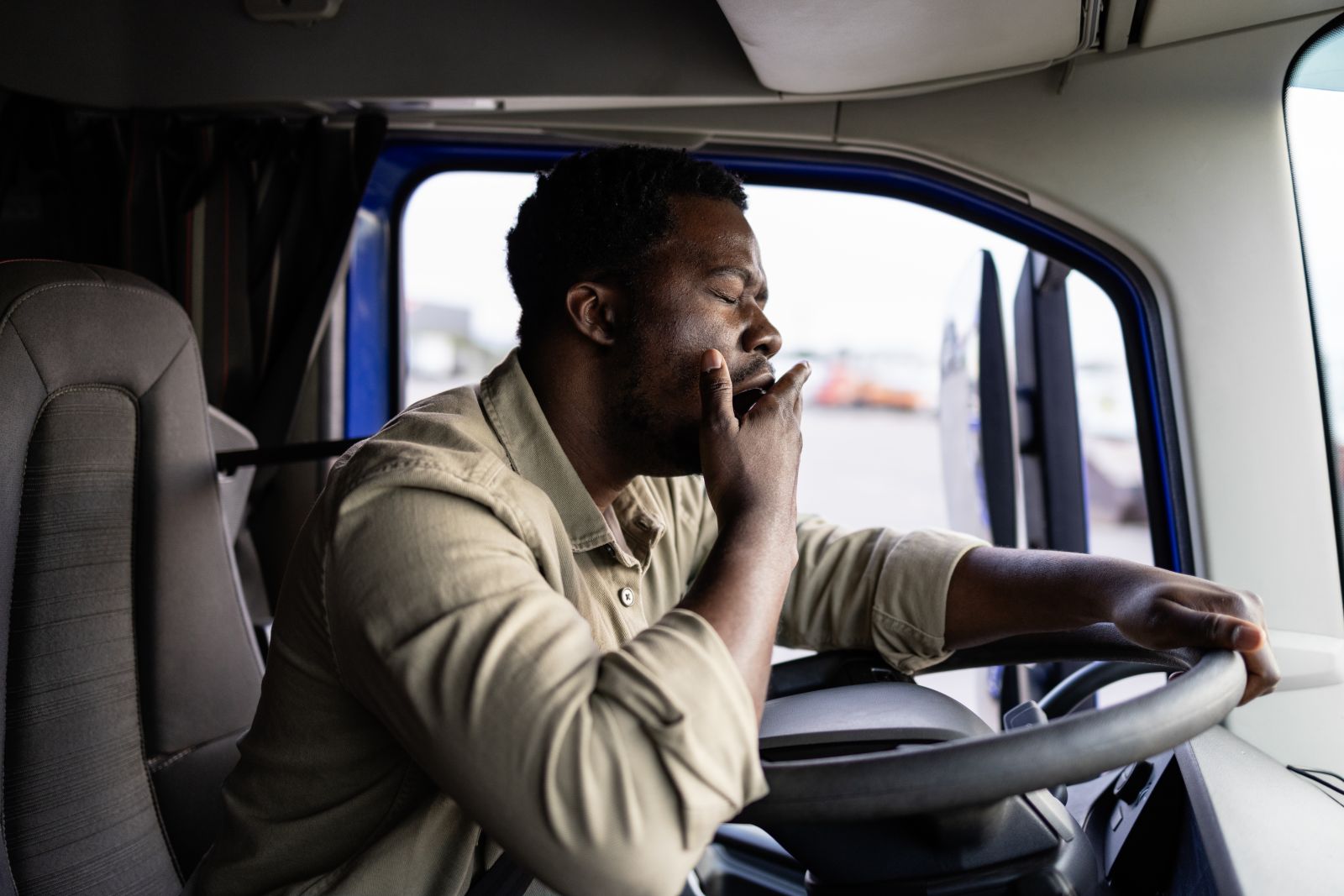 A black truck driver yawning while driving sleepy
