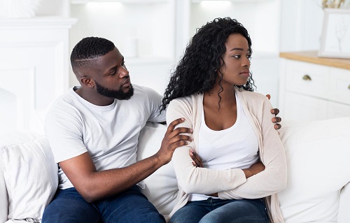 Black couple in bedroom with male partner appearing to validate his female partner's emotions