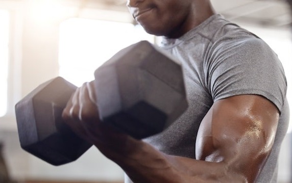 Partial view of a black male performing weight training for muscle building and strength