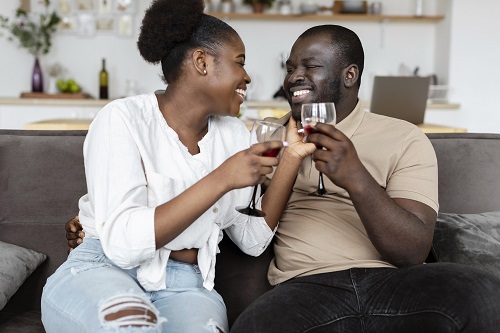 Balck couple sitting on a sofa having drinks and quality time together