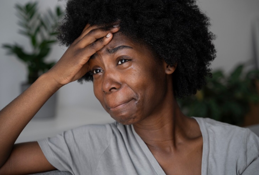 A young African woman looking sad and depressed following receipt of autoimmune disorder diagosis