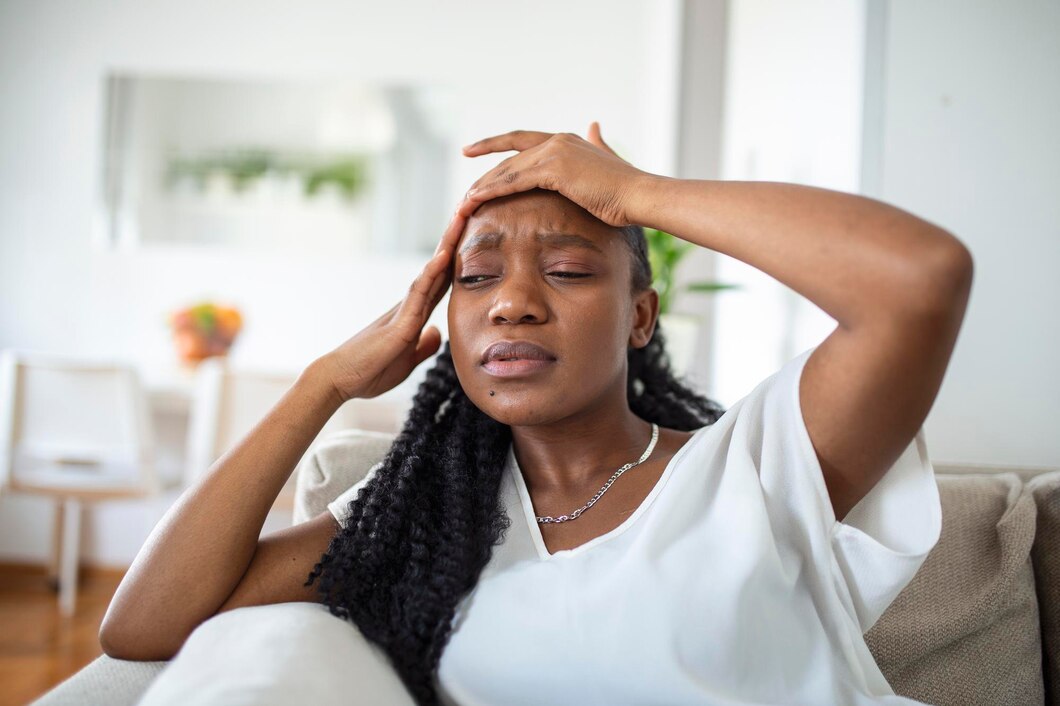 Young black girl with chronic daily headache sitting on a couch at home